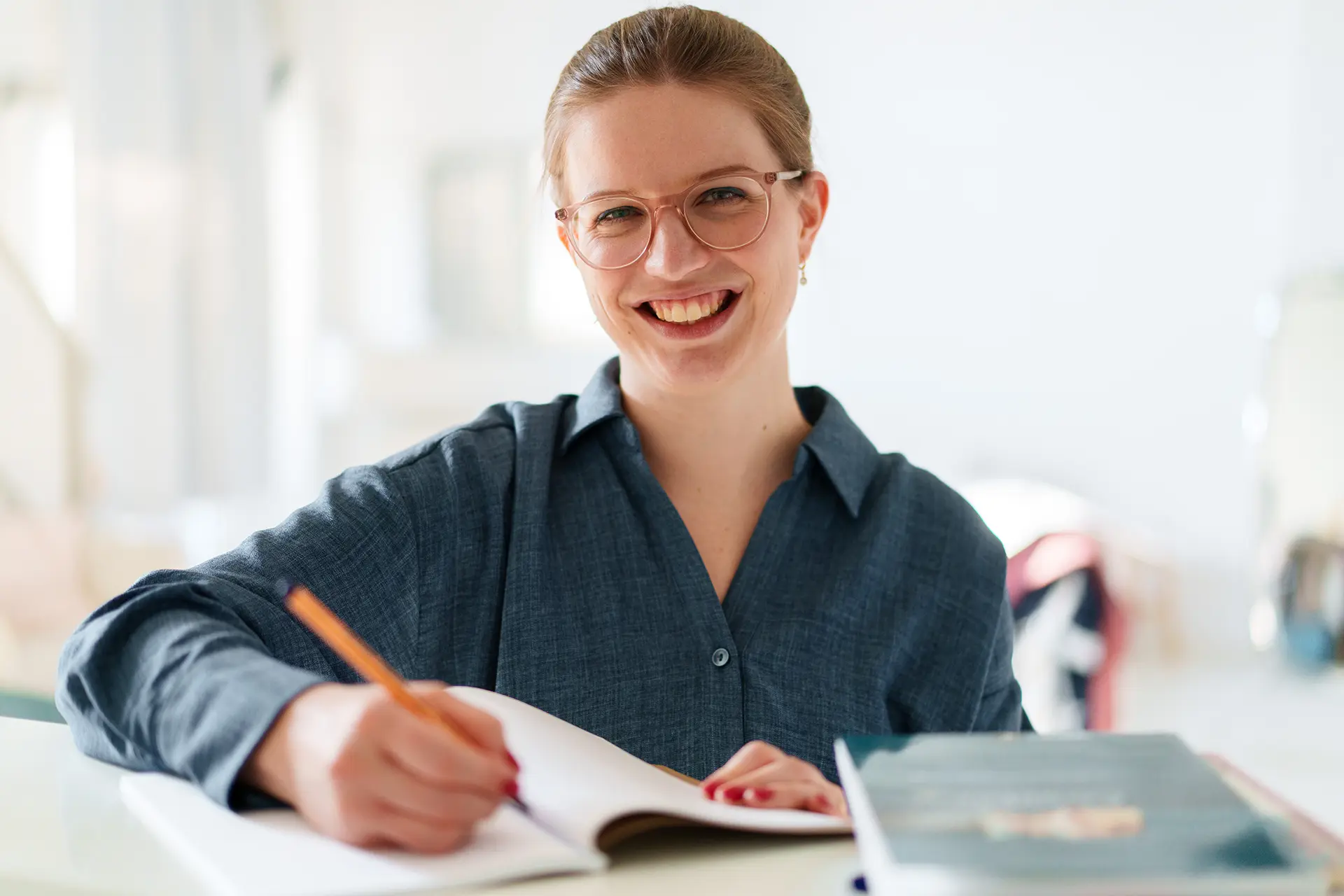 Saskia Fernandes l&auml;chelnd am Schreibtisch